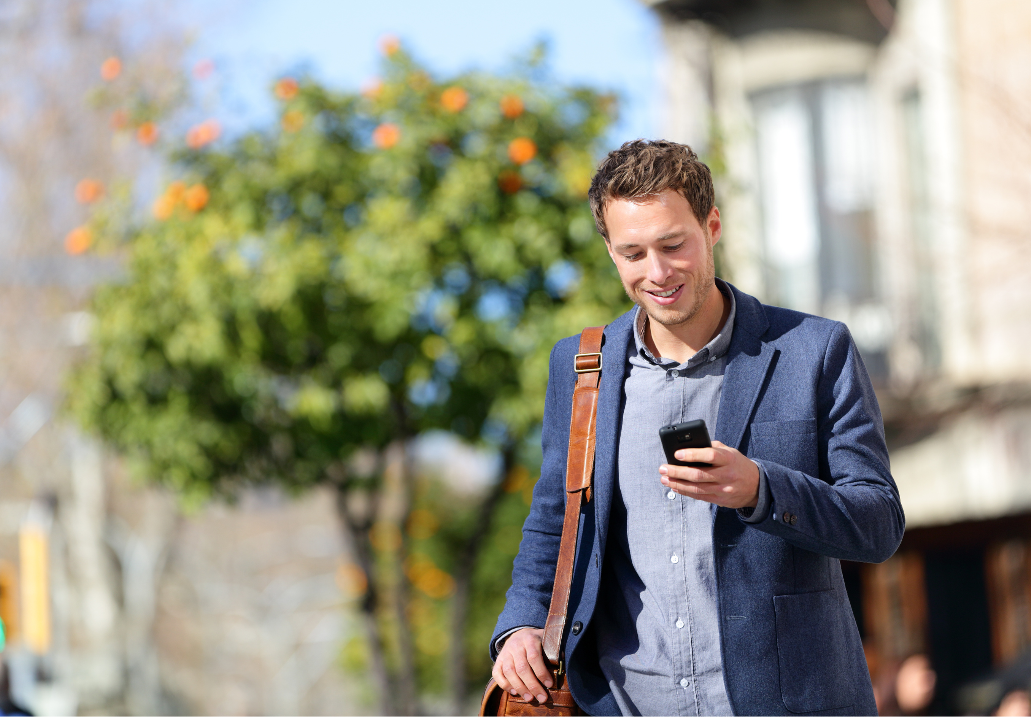 Man outside looking at phone happy