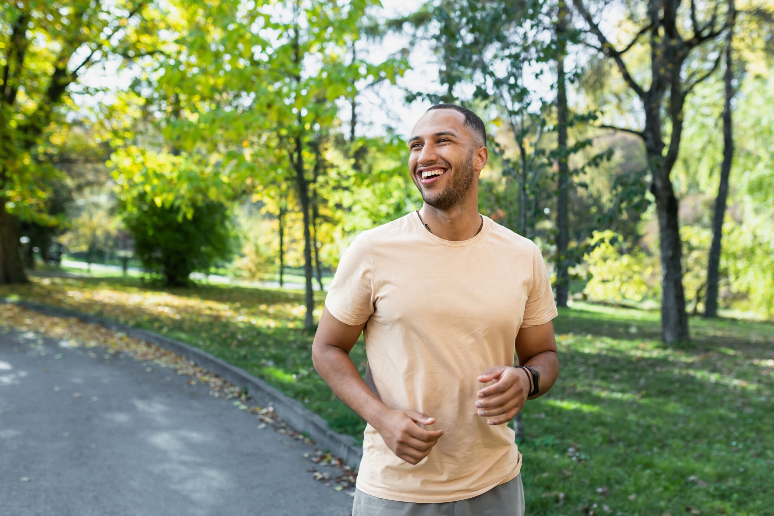 A smiling man jogs through a sunlit park in North Texas, illustrating the mental health breakthrough and sense of peace possible through psychedelic-assisted therapy at DreamWork Wellness Center.